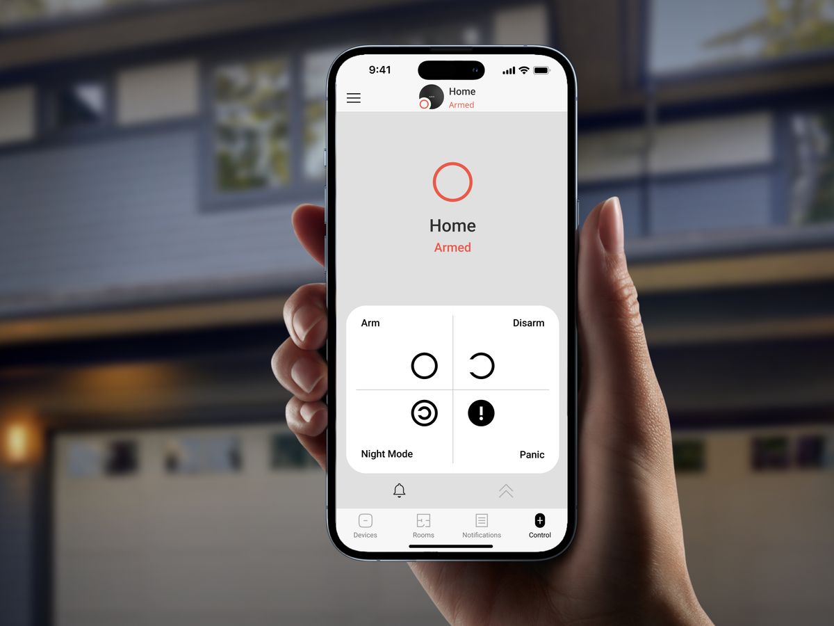 Handy-App in der Hand vor dem Haus